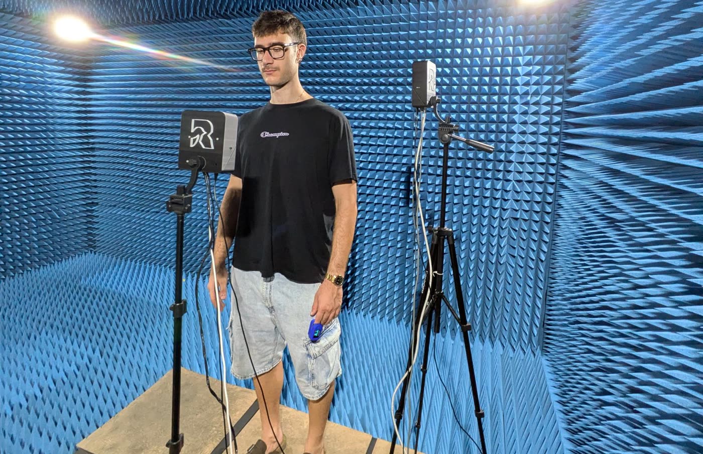 A volunteer standing in an anechoic chamber between two radars on tripods, one at chest height and one higher, aimed at the neck