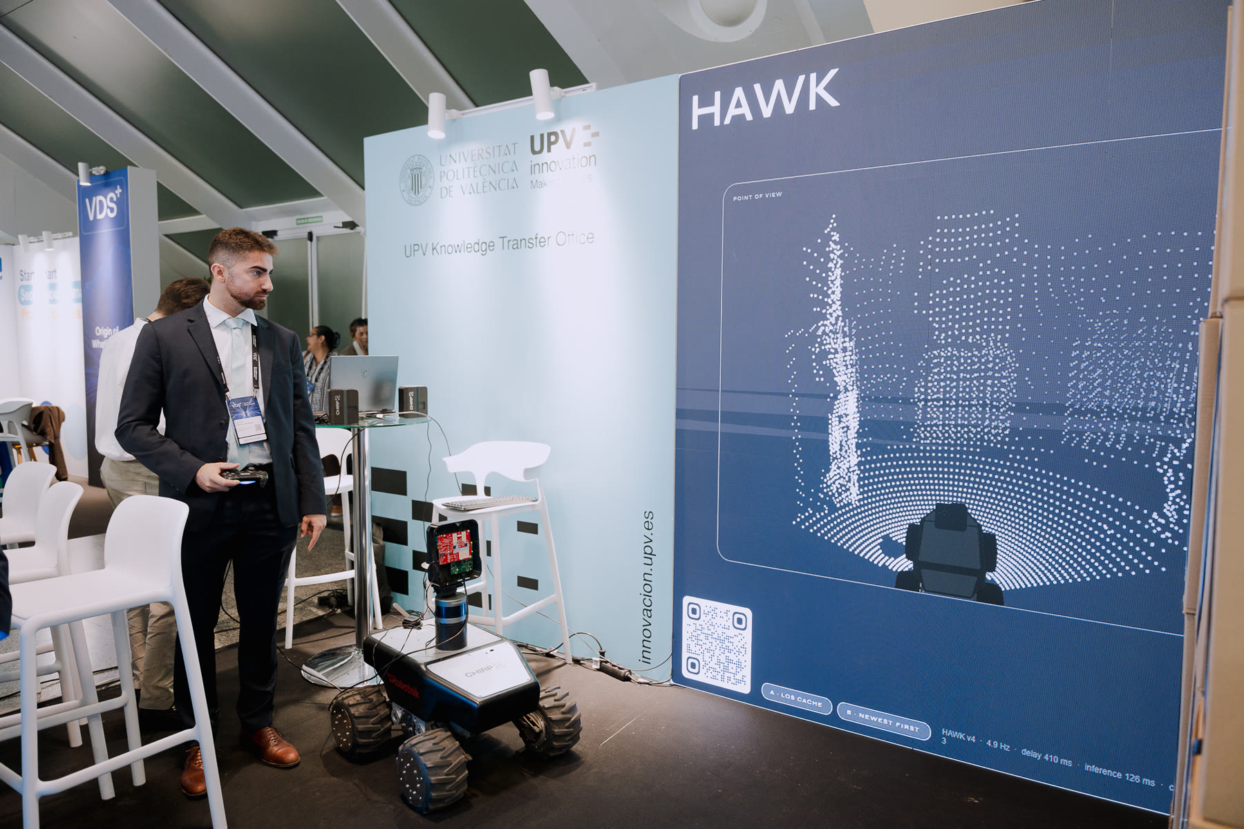 The HAWK display on the Universitat Politècnica de València stand, with the rover in front of it and a CHIRP team member beside it