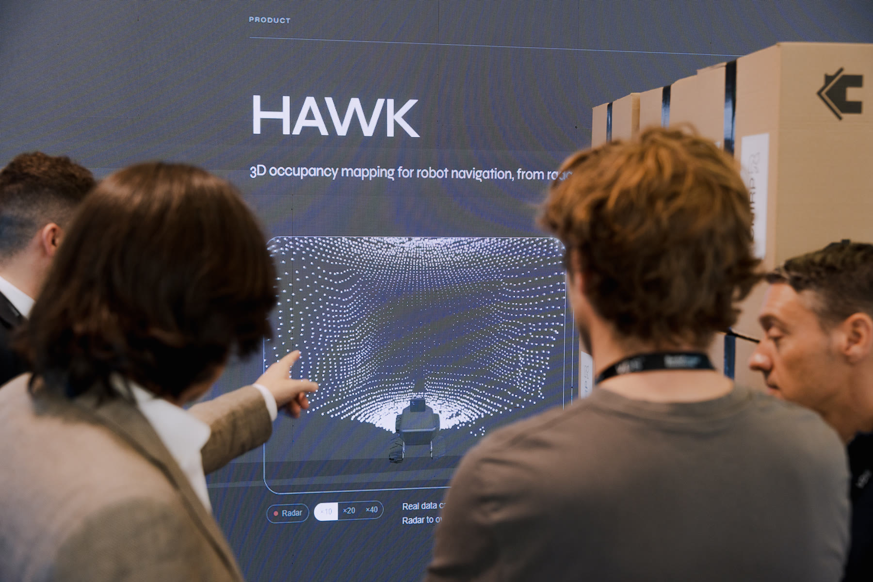 Visitors in front of the HAWK screen, one of them pointing at the radar point of view