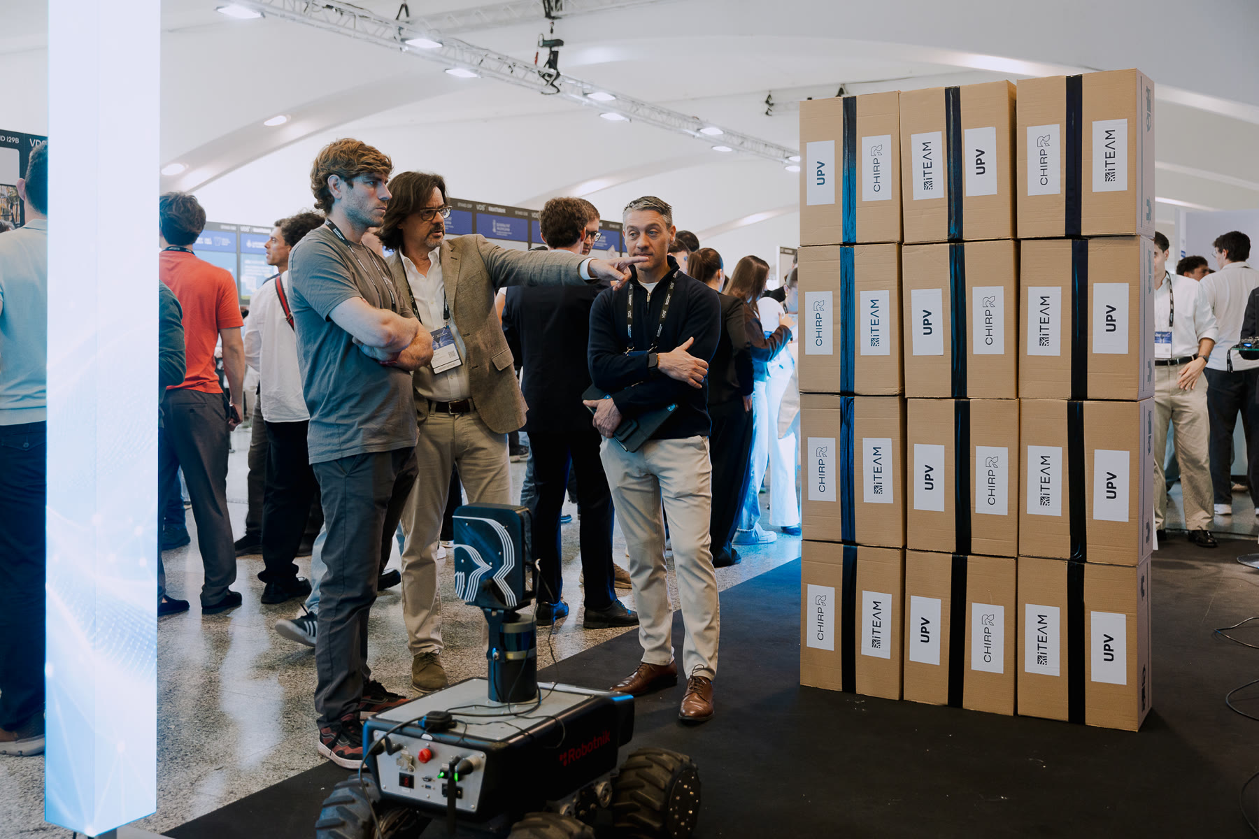 Visitors on the exhibition floor of Valencia Digital Summit 2026, next to the HAWK rover and a stack of UPV, iTEAM and CHIRP boxes